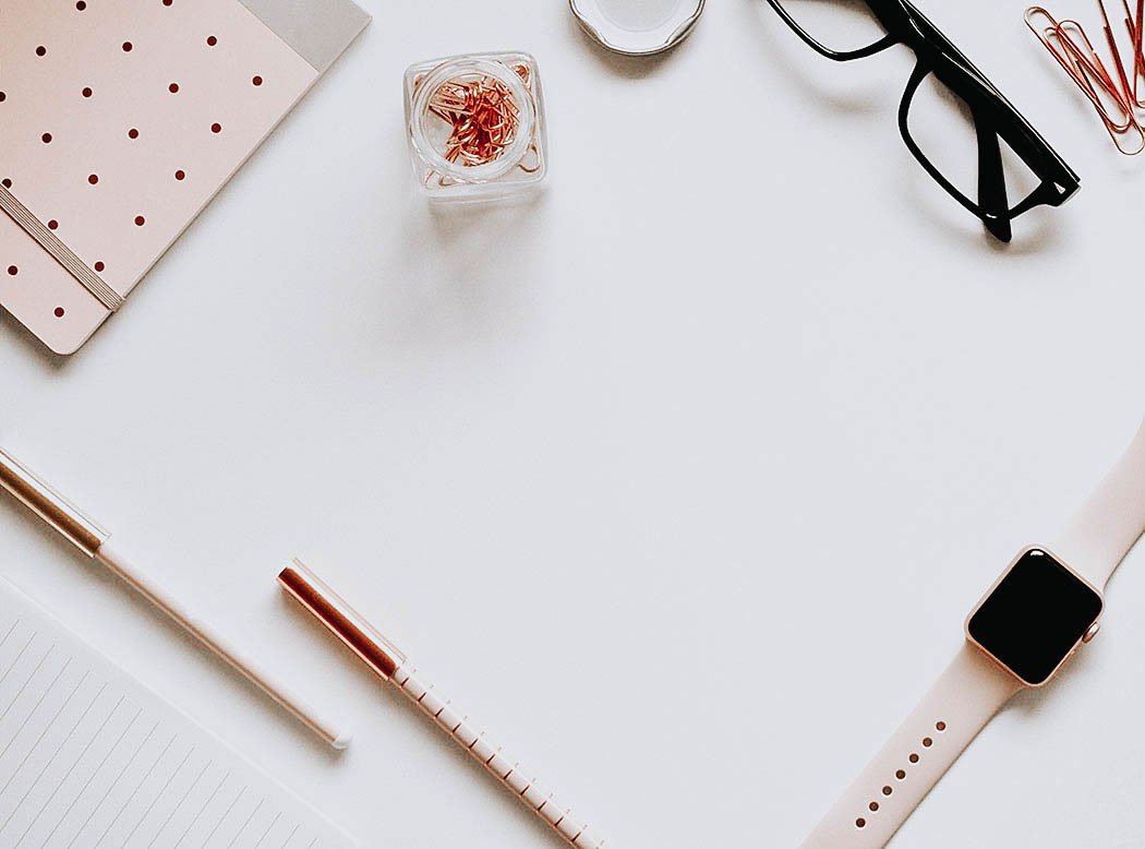 Escritorio con libretas, reloj, gafa y lápices para planificar la gestión de las redes sociales un emprendedora